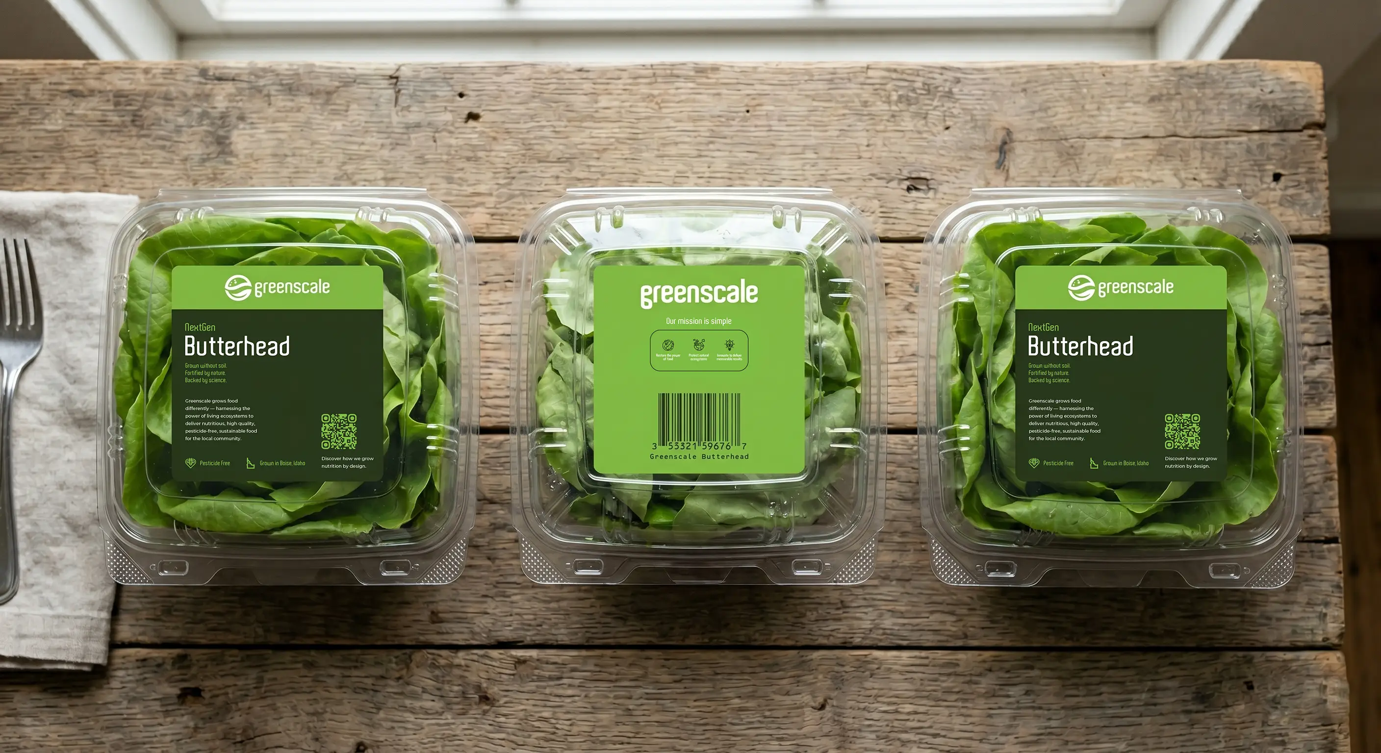 Greenscale butterhead lettuce clamshells stacked on a wooden crate
